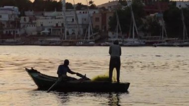 Nil nehrindeki balıkçılar, küçük ahşap bir teknede balık ağıyla balık avlıyorlar.