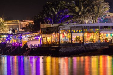 Gece kahvesinden gelen suda renkli ışıklar yansıyor.