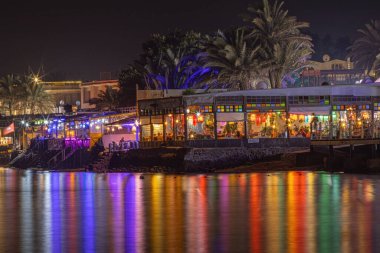 Gece kahvesinden gelen suda renkli ışıklar yansıyor.