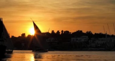 Günbatımında Nil 'de geleneksel felucca yelkenlisi, Aswan, Mısır