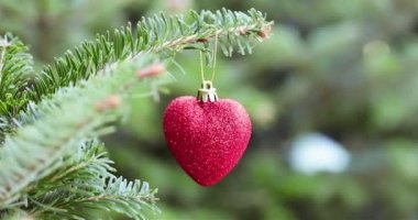 Kırmızı kalp ağaçtaki Noel oyuncağını şekillendirdi. Noel ve yeni yıl dekorasyonu.