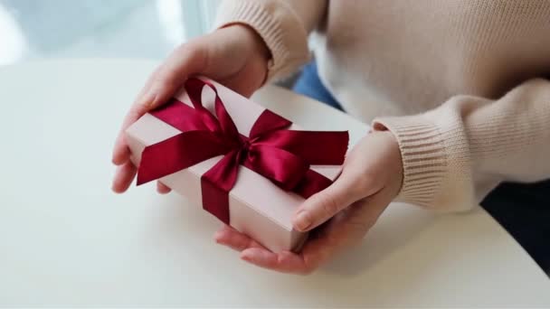 女人的手打开礼物的包装 把柔软的粉红缎带紧紧地系在一起 — 图库视频影像
