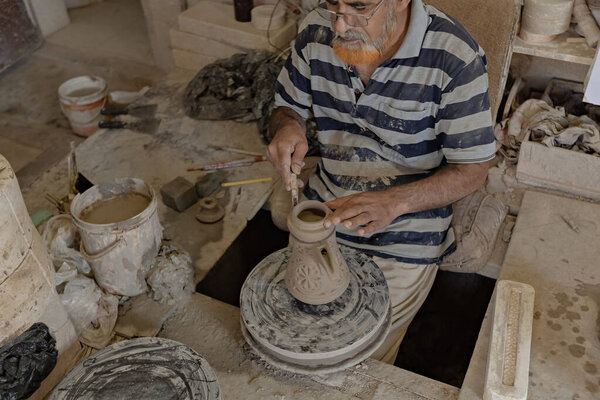 Man at pottery workshop. Arab man producing pitcher from clay at pottery shop in Bahrain