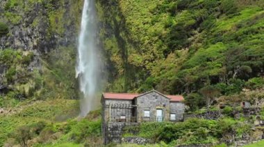 Flores İslamd Azores Portekiz 'de yanında şelale olan dağlarda küçük taş bir ev.