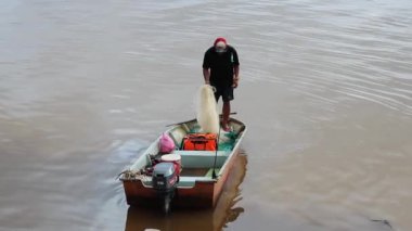 Malezyalı balıkçı, Sarawak nehri Borneo Malezya 'da bir ağla balık yakalamaya çalışıyor