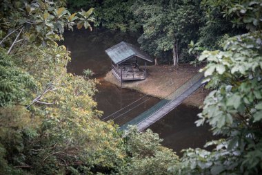 Borneo yağmur ormanlarının güzel doğası gölün üzerindeki asma köprü ve ahşap kulübe Sandakan Malezya