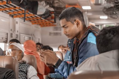 Bangladeş halkı bir tren yolculuğunda Bangladeş demiryollarında genç adam akıllı telefonu bir trende kaydırıyor.
