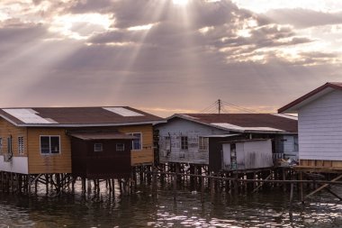 Fishing village houses over the water garbage poor areas in Sabah province in Malaysia clipart