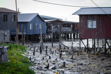 Fishing village houses over the water garbage poor areas in Sabah province in Malaysia clipart