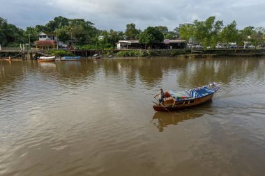 Kuching Borneo Malezya 'daki Sarawak nehrindeki geleneksel teknede kayıkçı.