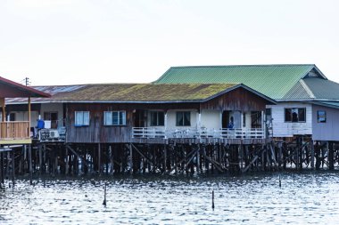 Fishing village houses over the water garbage poor areas in Sabah province in Malaysia clipart