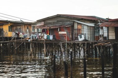 Fishing village houses over the water garbage poor areas in Sabah province in Malaysia clipart