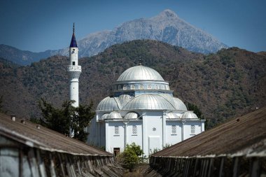 Arka planda dağlar ve Antalya Çemberi çevresinde yeşil evler bulunan Cirali camii