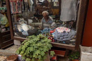 Tailor shop with a worker inside sitting at stitching machine in the old town of Skopje North Macedonia