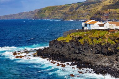 Bright houses on the cliff at Atlantic ocean coast in Azores islands Portugal clipart