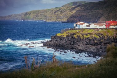 Bright houses on the cliff at Atlantic ocean coast in Azores islands Portugal clipart