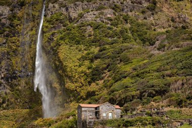 Flores İslamd Azores Portekiz 'de yanında şelale olan dağlarda küçük taş bir ev.