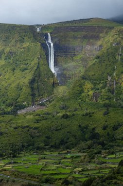 Flores Adası Azores Portekiz 'deki yeşil dağlardaki şelalenin nefes kesici manzarası.