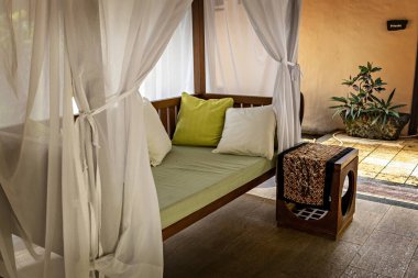 Güneş yatağı, beyaz perdeleri ve sehpası olan lüks bir otelde özel misafir odası.