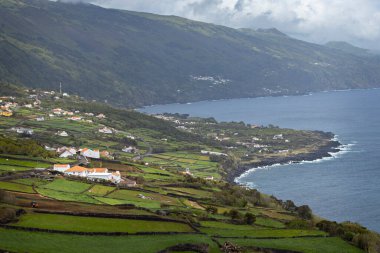 Breathtaking view of the small village and green meadows from the cliff at Pico island Azores Portugal clipart