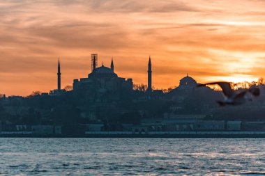 Beautiful sunset at Bosphorus mosque minaret silhouette, boats on the water Sultanahmet area of Istanbul Turkey clipart