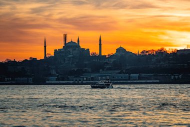 Beautiful sunset at Bosphorus mosque minaret silhouette, boats on the water Sultanahmet area of Istanbul Turkey clipart