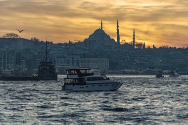 Beautiful sunset at Bosphorus mosque minaret silhouette, boats on the water Sultanahmet area of Istanbul Turkey clipart