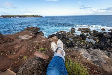 Woman's legs in front of the ocean view relaxing by the ocean clipart