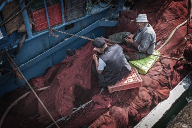 Moroccan fishermen in the port of Essaouira fixing fishing nets Morocco clipart