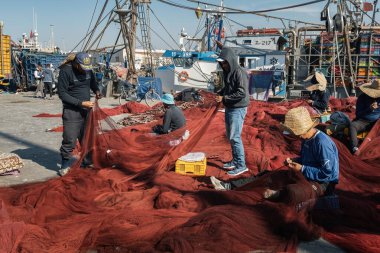 Essaouira limanındaki Faslı balıkçılar Fas balıkçı ağlarını tamir ediyor.