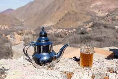 Berber tea pot and the cup pf tean with mountain view Atlas mountains Morocco clipart