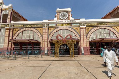Dakar şehrindeki tarihi kontral tren istasyonu cephesi ve Senegal treniyle seyahat eden insanlar.