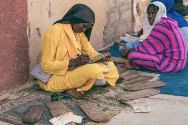  Geleneksel kıyafetler giyen Afrikalı genç bir kadın St. Louis Senegal 'deki tahta tahtaya İslami kutsal metinler yazıyor.