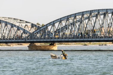 Senegali balıkçısı kayıkta demir köprüye yakın ağlarla balık tutuyor.
