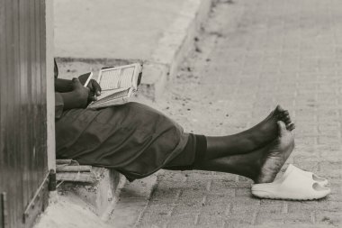 Kaldırımda oturan ve Senegal Afrika kitabını okuyan adam.