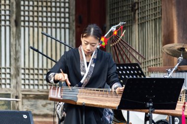 Gayageum (veya Kayagum) çalan Koreli kadın, geleneksel Koreli tel enstrümanı