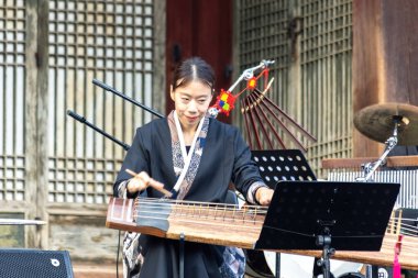Gayageum (veya Kayagum) çalan Koreli kadın, geleneksel Koreli tel enstrümanı