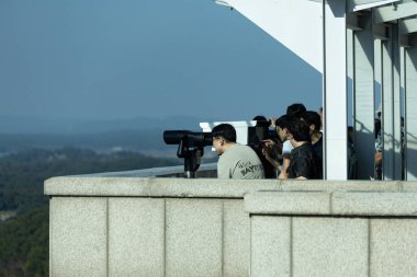 İnsanlar Kuzey Kore 'yi Güney Kore' deki askersiz bölgeden nehrin karşı kıyısında izliyor.