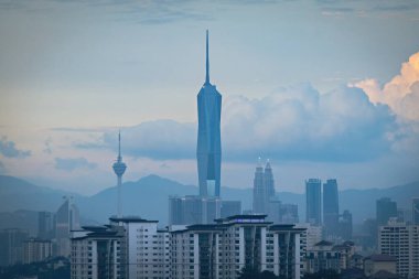 Gün batımında Kuala Lumpur şehir merkezinde gökdelenler ve kuleler gün batımında bulutlu gökyüzüne karşı