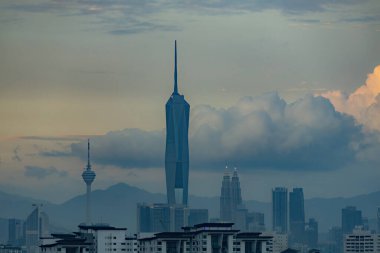 Gün batımında Kuala Lumpur şehir merkezinde gökdelenler ve kuleler gün batımında bulutlu gökyüzüne karşı