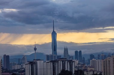 Gün batımında Kuala Lumpur şehir merkezinde gökdelenler ve kuleler gün batımında bulutlu gökyüzüne karşı