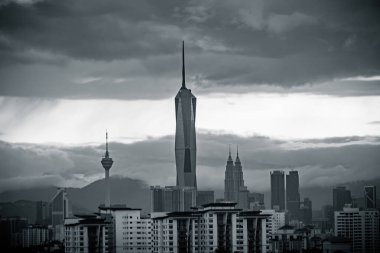 Gün batımında Kuala Lumpur şehir merkezinde gökdelenler ve kuleler gün batımında bulutlu gökyüzüne karşı