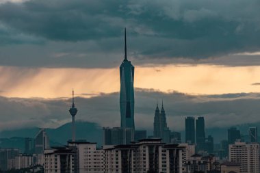 Gün batımında Kuala Lumpur şehir merkezinde gökdelenler ve kuleler gün batımında bulutlu gökyüzüne karşı