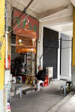 Bir kuş ve Çinli bir adamla kafes Macau 'daki evinin yakınında.