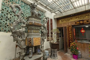 Macau 'daki geleneksel Çin tapınağı avlusunda ejderhalarla süslenmiş tütsü yakıcısı, şairane el yazısı ve bonsai bitkileriyle çevrili.