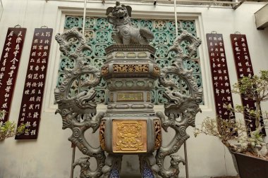 Macau 'daki geleneksel Çin tapınağı avlusunda ejderhalarla süslenmiş tütsü yakıcısı, şairane el yazısı ve bonsai bitkileriyle çevrili.
