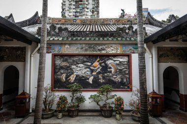 Koi balığı ve dalga motifleriyle geleneksel Çin duvar resmi, bonsai bitkileri tarafından çerçevelenmiş ve Makao 'daki Templo de Kun Iam Tong' da tarihi mimari.