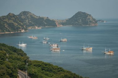Endonezya 'nın Labuan Bajo kasabası Komodo' da su üzerinde kulübeleri olan tepelerin ve körfezin havadan görüntüsü.