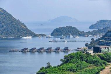 Endonezya 'nın Labuan Bajo kasabası Komodo' da su üzerinde kulübeleri olan tepelerin ve körfezin havadan görüntüsü.