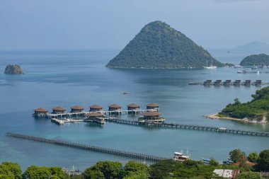 Endonezya 'nın Labuan Bajo kasabası Komodo' da su üzerinde kulübeleri olan tepelerin ve körfezin havadan görüntüsü.
